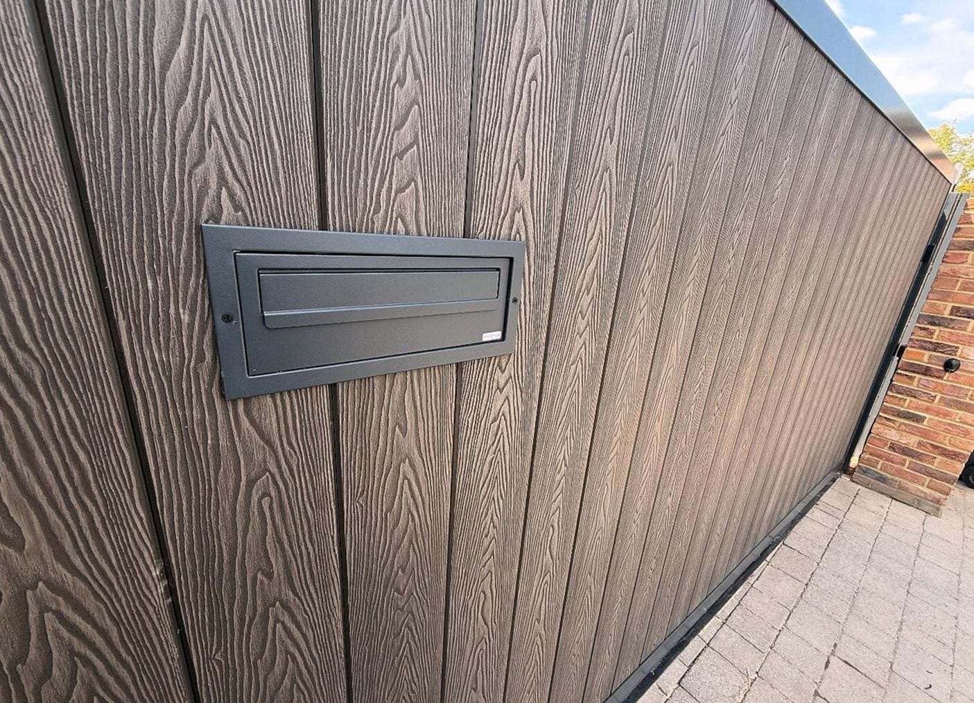 Wood-grain composite gate boards with a black mail slot set into the panel